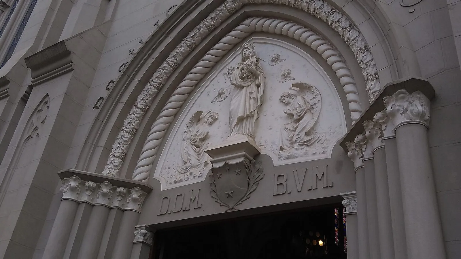 Portal em arco da Basílica de Nossa Senhora do Carmo, no Centro de Campinas, com relevo de Nossa Senhora cercada de anjos e as letras D.O.M. e B.V.M.