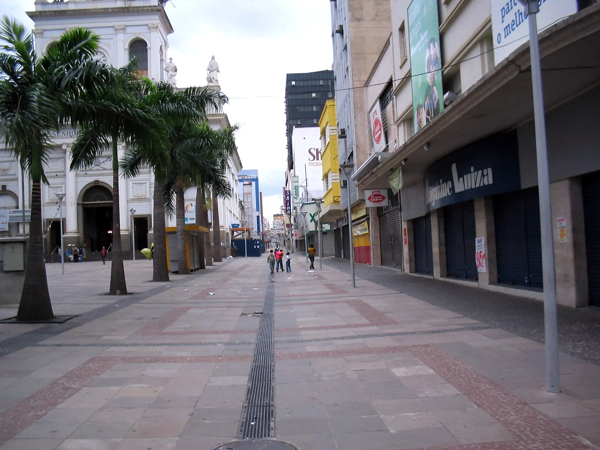 Praça no centro de Campinas com palmeiras, calçadão e edifícios ao fundo em dia nublado