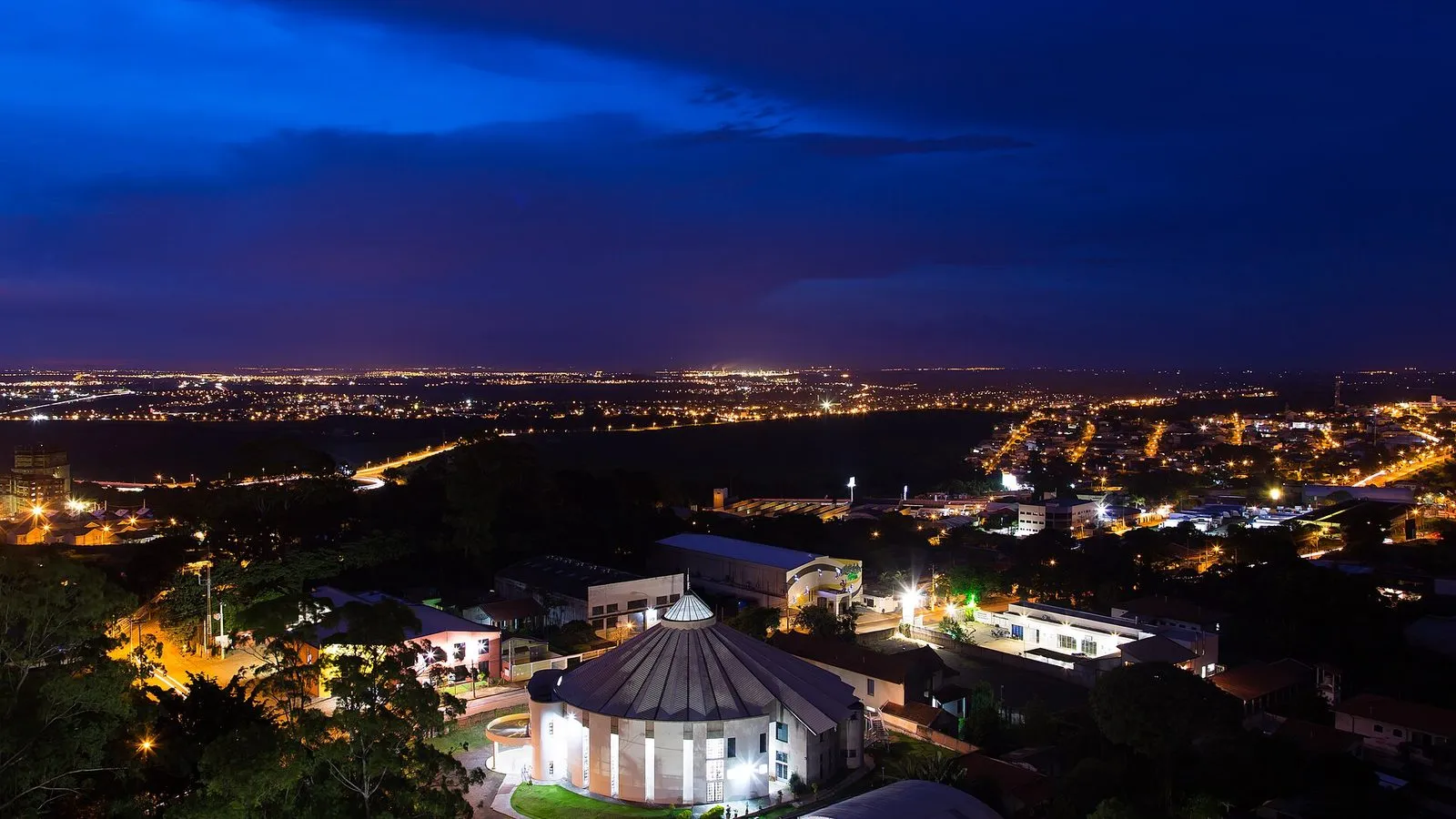 Vista noturna de Campinas do alto, com as luzes da cidade até o horizonte