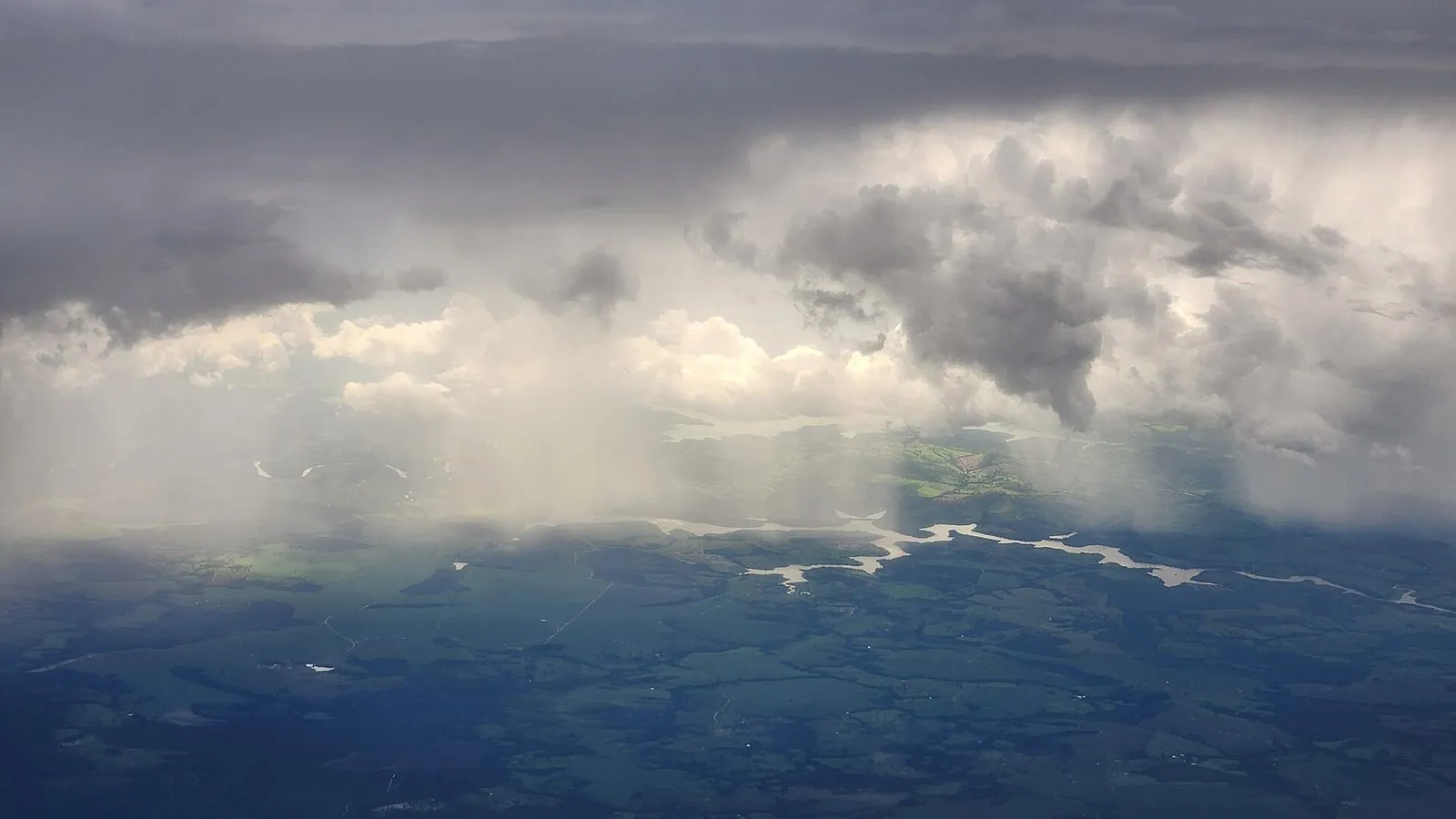 Cortinas de chuva caindo de nuvens escuras sobre a região de Campinas, vistas de um avião