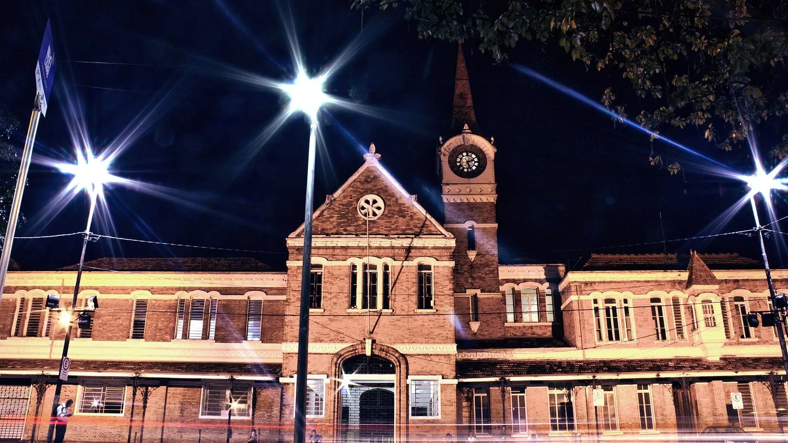 Fachada da Estação Cultura iluminada à noite, com a torre do relógio
