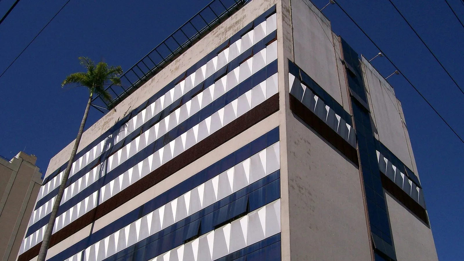 Prédio da unidade atual do Hospital Vera Cruz em Campinas, com fachada de faixas azuis e brancas, visto de baixo contra o céu azul