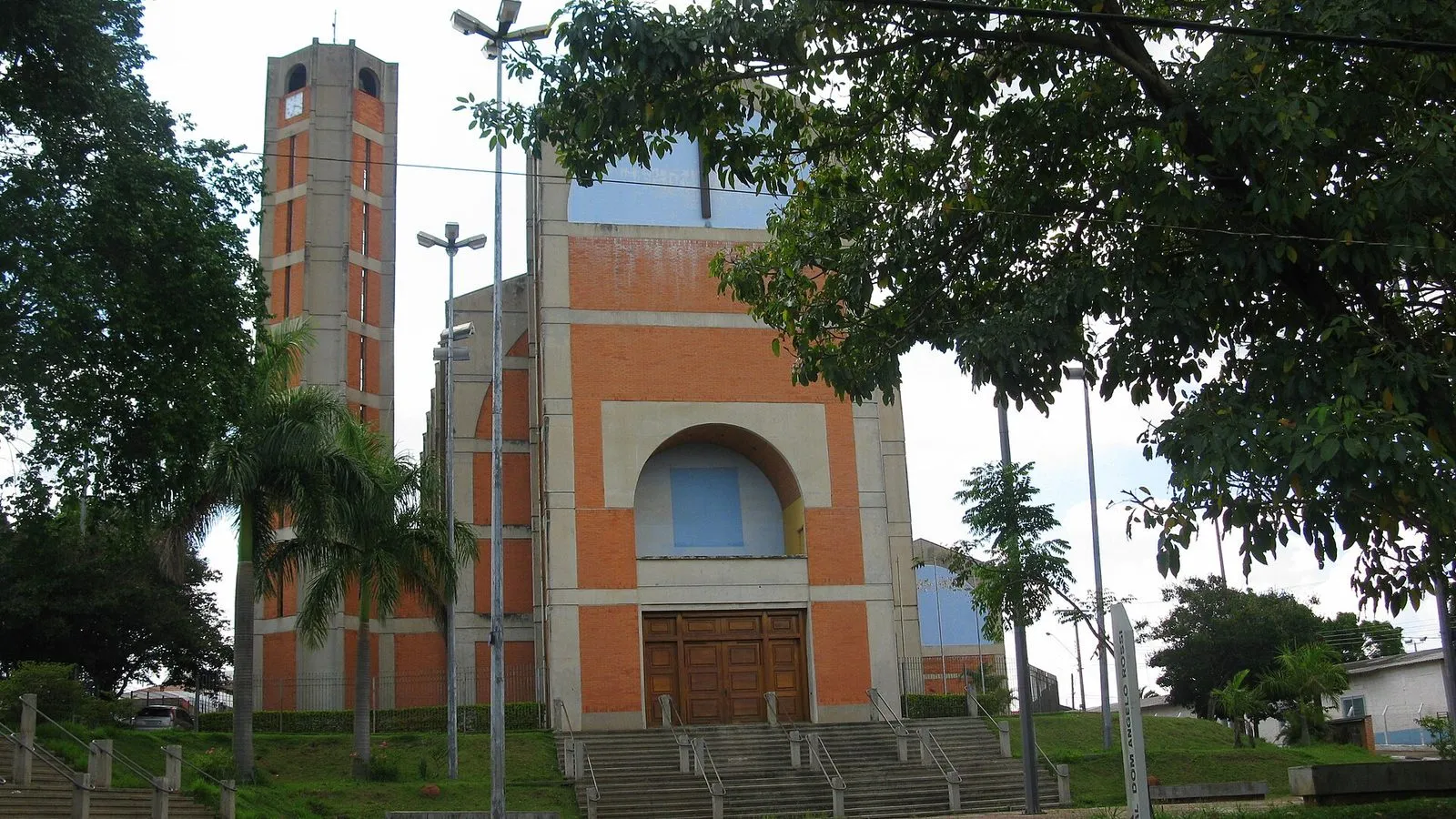 Fachada da Igreja Nossa Senhora de Guadalupe, em Campinas, com torre de tijolos e escadaria cercada por árvores