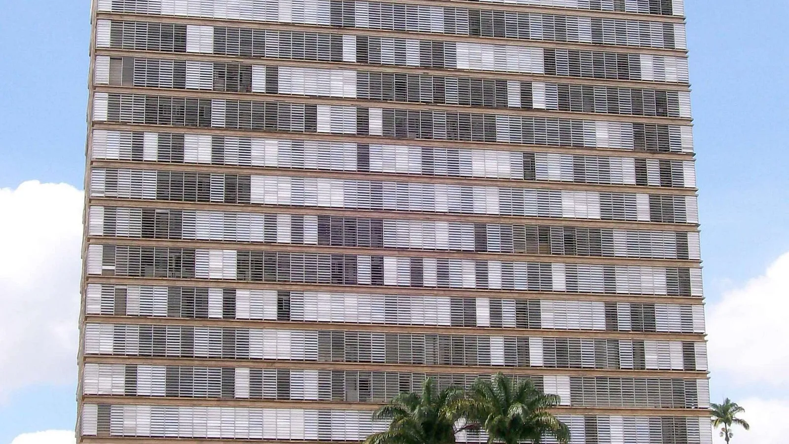 Fachada do Palácio dos Jequitibás, prédio alto da sede da Prefeitura de Campinas, com palmeiras na base
