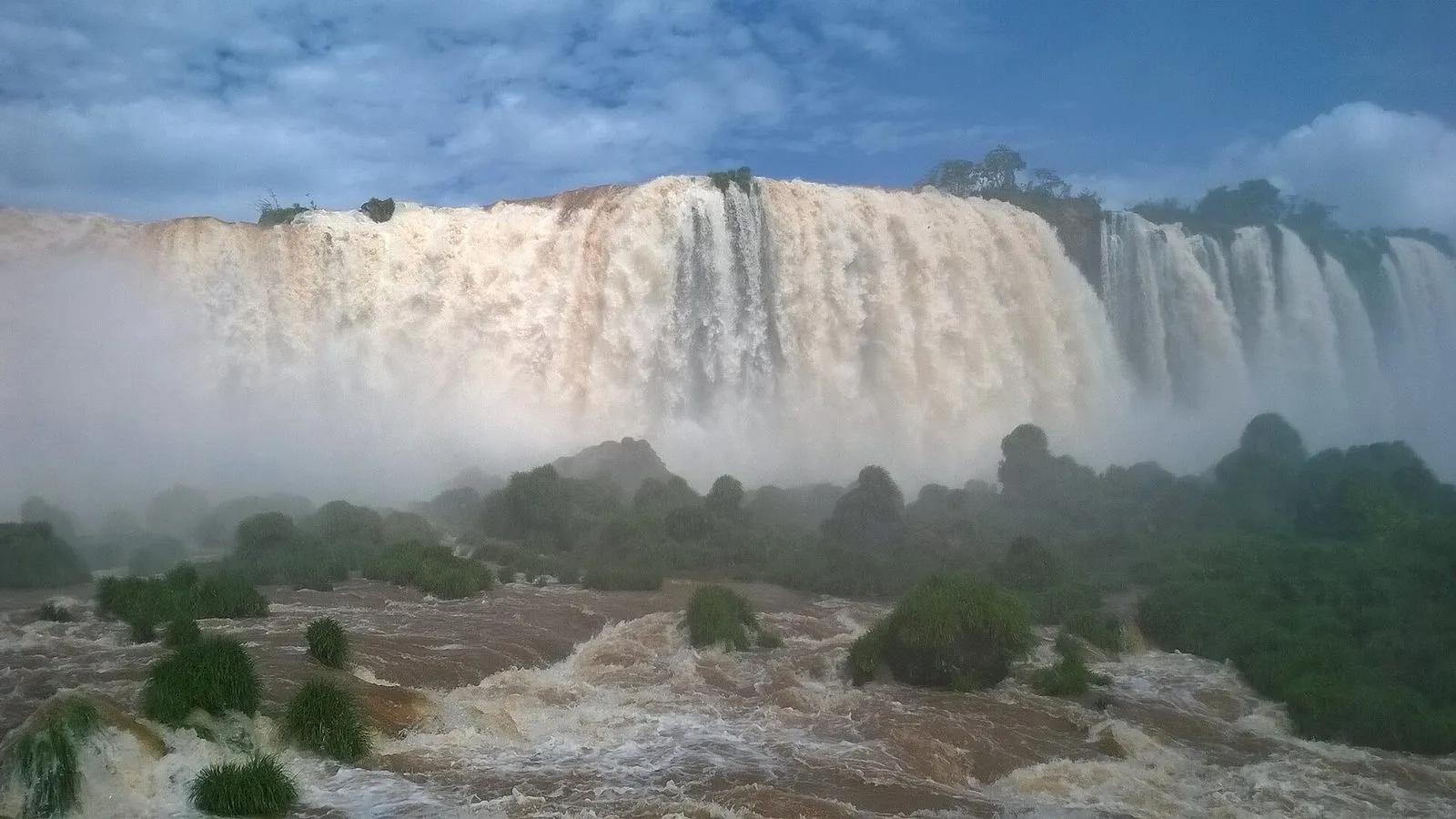A Garganta do Diabo vista do lado brasileiro em época de rio cheio, com a água barrenta e muita névoa.