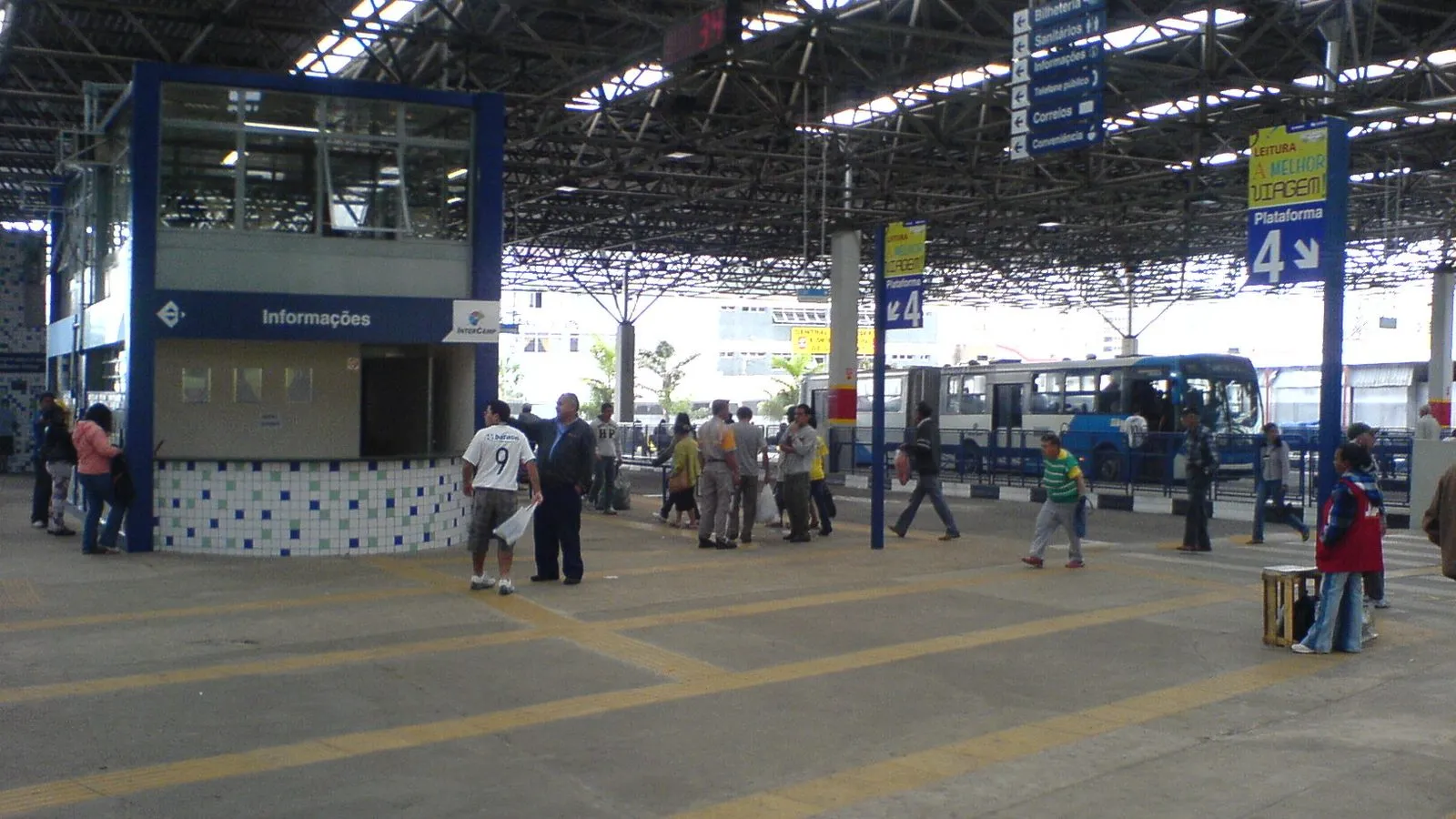 Área de plataformas do Terminal Central de Campinas, com posto de informações e ônibus ao fundo